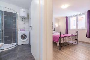 a bathroom with a bed and a washing machine at Apartment Taja in Ližnjan