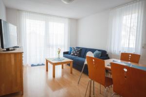 a living room with a blue couch and a table at Strandpension Mäder in Uhldingen-Mühlhofen