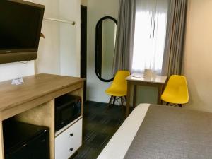 a hotel room with a bed and two yellow chairs at Downtown San Diego Lodge in San Diego