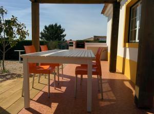 einen weißen Tisch und Stühle auf einer Terrasse in der Unterkunft Casas das Amoreiras in Aldeia do Meco