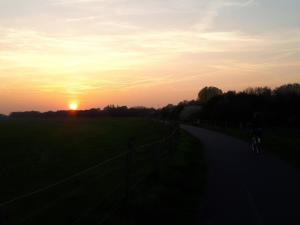 a person riding a bike down a road at sunset at Schöne komplette Ferienwohnung in Wesel in Wesel
