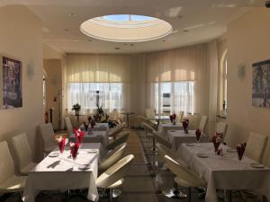 a dining room with white tables and white chairs at Eastbourne Riviera Hotel in Eastbourne