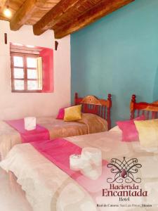 a bedroom with two beds and a blue wall at Hotel Hacienda Encantada in Real de Catorce