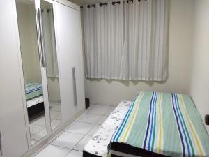 una piccola camera con letto e specchio di Apartamento Guarapari, WI-FI, Vista do Mar, Praia do Morro,100 metros do Mar a Guarapari
