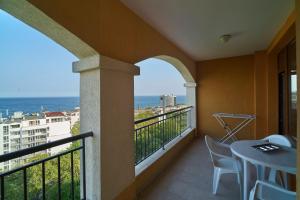 een balkon met een tafel en stoelen en uitzicht op de oceaan bij Sea Panorama Apartments Golden sands in Goudstrand