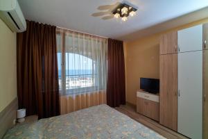 a bedroom with a bed and a window and a television at Sea Panorama Apartments Golden sands in Golden Sands
