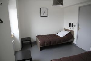 a small bedroom with a bed and a chair at Auberge Saint Jacques in Saint-Alban-sur-Limagnole