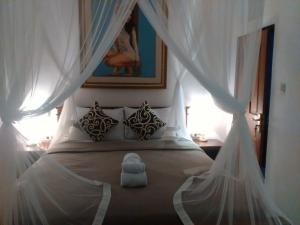 - une chambre avec un lit à baldaquin blanc dans l'établissement Shiva House, à Ubud