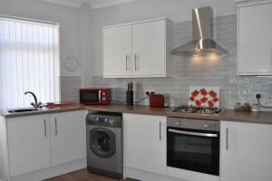 a kitchen with white cabinets and a stove top oven at Adelaide Apartments in Blackpool