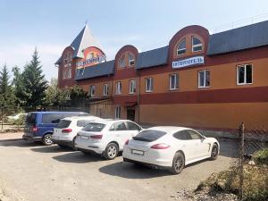 drei Autos auf einem Parkplatz vor einem Gebäude geparkt in der Unterkunft Inter Hotel in Ternopil