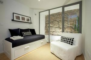 um quarto com uma cama e uma cadeira branca em Liiiving in Porto | Downtown Terrace Apartment no Porto
