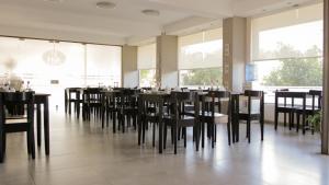 a dining room with black chairs and tables and windows at Palace Hotel in Nueve de Julio