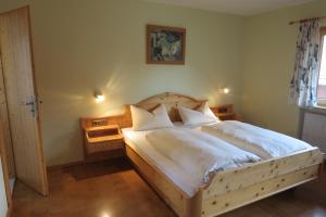 a bedroom with a wooden bed with white sheets and pillows at Gästehaus Peter Wiedemann in Lenggries