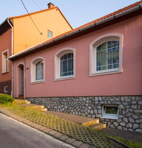 a red and yellow house with a stone wall at Boros Vendégház Eger in Eger