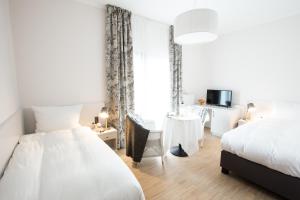 a white bedroom with two beds and a window at Hotel Strand26 an der Ostsee in Ostseebad Nienhagen