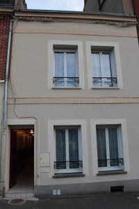 a white building with three windows and a door at Le Ch'ti Champenois in Épernay