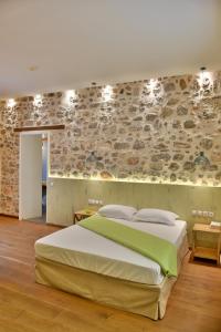 a bedroom with a large bed and a stone wall at Manolia in Hydra