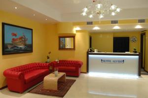 una sala d'attesa con divani rossi e un podio di Hotel Alverì a Mestre