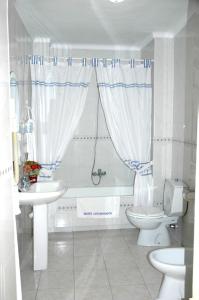 a bathroom with a tub and a sink and a toilet at Hotel Restaurante Logasasanti in Andújar