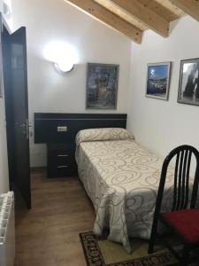 Un pequeño dormitorio con una cama y una silla. en kilometro 15, en Amenal