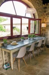 a table and chairs in a room with windows at Le Domaine du Fayet in Sanilhac