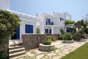 een wit huis met blauwe ramen en een tuin bij Carlo Bungalows in Agios Ioannis