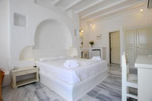 a white bedroom with a large bed and a kitchen at Carlo Bungalows in Agios Ioannis