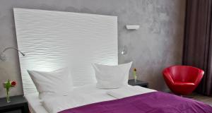 ein Schlafzimmer mit einem weißen Bett und einem roten Stuhl in der Unterkunft Artim Hotel in Berlin