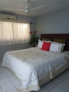 ein Schlafzimmer mit einem großen weißen Bett mit roten Kissen in der Unterkunft Sunset Quay in Rarotonga