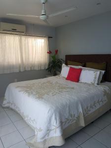 a bedroom with a large white bed with red pillows at Sunset Quay in Rarotonga