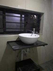 a white sink on a black counter in a bathroom at Unik studio Apartments in Lusaka