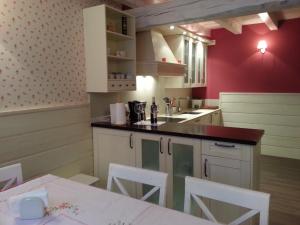 a kitchen with red walls and white cabinets and a table at Casa Rural el Rincon de Maria in Villoslada de Cameros