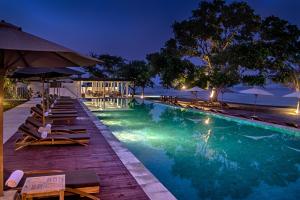 a swimming pool with chairs and umbrellas at night at Living Asia Resort and Spa in Senggigi