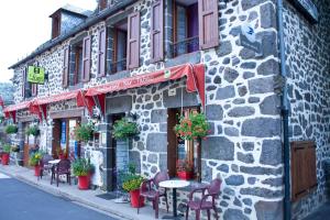 een stenen gebouw met tafels en stoelen in een straat bij Hotel De La Poste in Saint-Martin-sous-Vigouroux