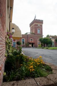 un bâtiment doté d'une tour d'horloge avec des fleurs devant lui dans l'établissement Hotel Candiani, à Casale Monferrato