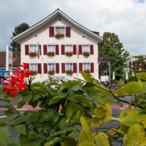 ein weißes Haus mit roten Rollläden in der Unterkunft Hotel Ristorante Schlössli in Luzern