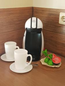 a coffee maker and two cups on a table at Agneta Apartamentai in Druskininkai