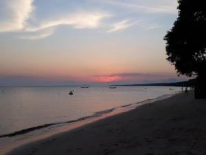 um pôr do sol numa praia com barcos na água em Pousada Villa Maria na Ilha do Mel
