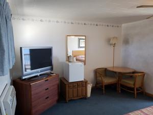 a room with a television on a dresser and a table at Algoma Beach Motel in Algoma
