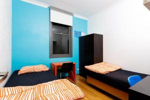 a room with two beds and a table and a window at South Yarra Hostel in Melbourne
