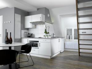 una cucina con armadi bianchi e tavolo con sedie di Appartements Le 32 a Strasburgo