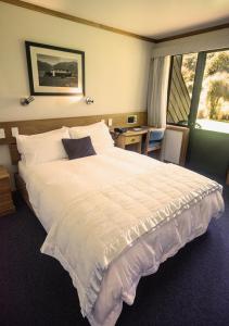 a bedroom with a large white bed with a window at Alpine Lodge in Saint Arnaud