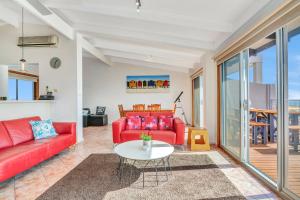 a living room with a red couch and a table at Queensland South - Aldinga Beach - C21 SouthCoast Holidays in Aldinga Beach