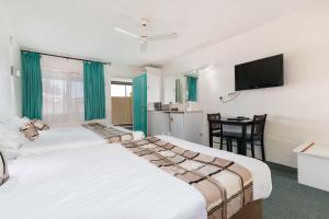 a hotel room with two beds and a television at Coffs Harbour Pacific Palms Motel in Coffs Harbour