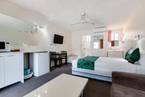 a hotel room with a bed and a kitchen and a table at Coffs Harbour Pacific Palms Motel in Coffs Harbour