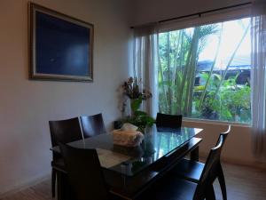 a dining room with a glass table and chairs and a window at Wesberly Apartments in Kuching