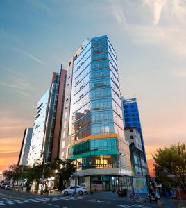 un edificio de cristal alto con un coche delante en Best Western Haeundae Hotel en Busan