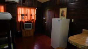 a kitchen with a white refrigerator and a tv at Hospedaje Rural Villa Santiago in Río Jiménez