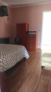 1 dormitorio con 1 cama y suelo de madera en Pousada Rosa, en Campos do Jordão