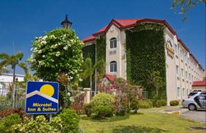 una señal frente a un edificio con una casa en Microtel by Wyndham Batangas en Santo Tomas